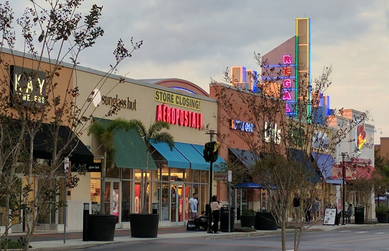 A row of stores including a store called Kay Jewelers, Sunglass Hut, Aeropostale, Lids. There is a Regal Cinema at the far right. 