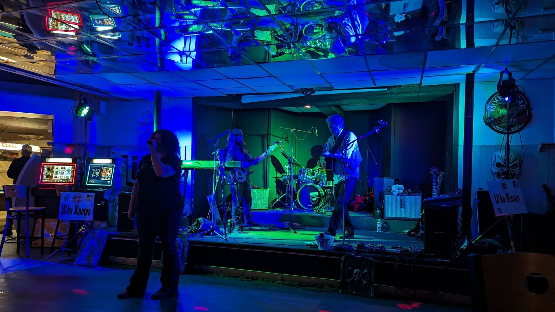 Band playing on stage with blue and green lighting in a venue.