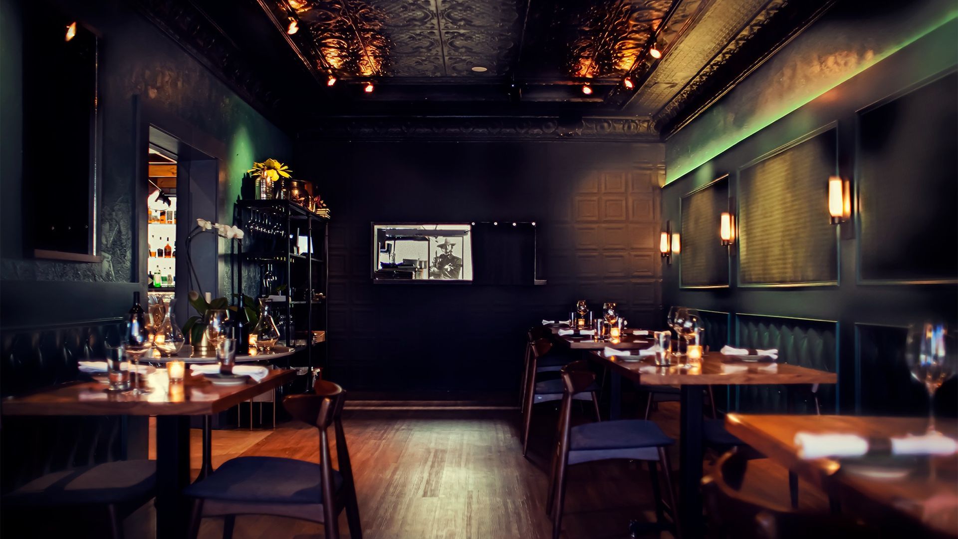 Dark restaurant interior with tables set for dining and soft lighting.