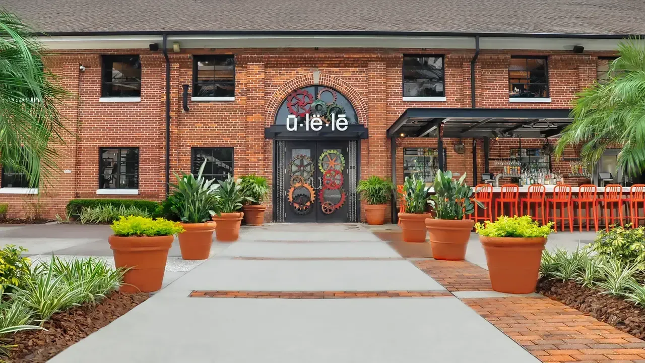 Restaurant exterior with brick facade, arched doorway, and potted plants.