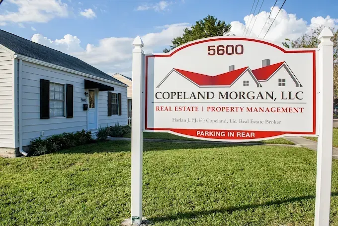 Copeland Morgan, LLC real estate sign in front of a white building on a sunny day