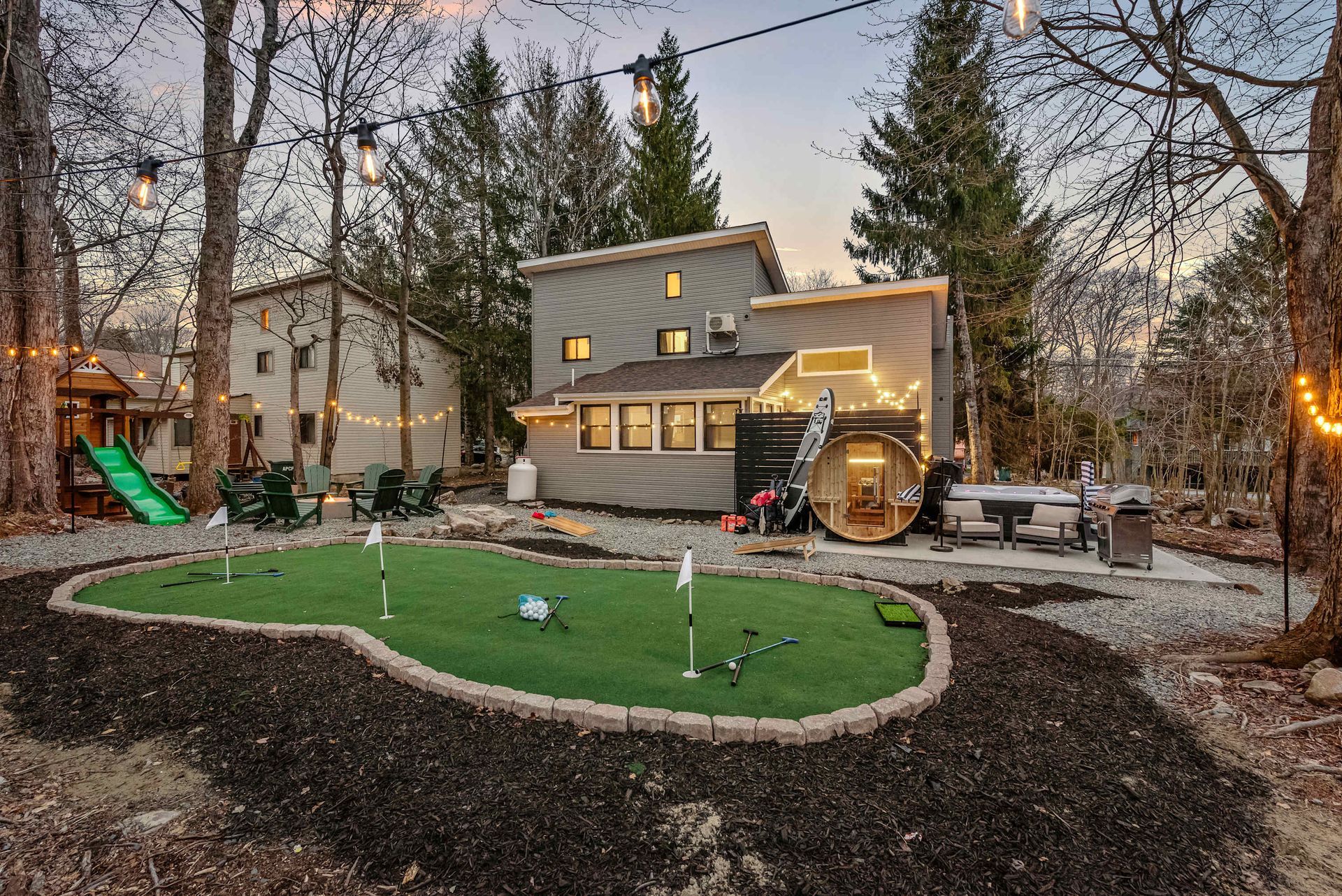 There is a putting green in the backyard of a house.