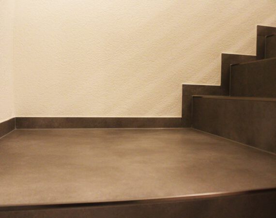 Graue Betontreppe vor hellbeiger Wand.