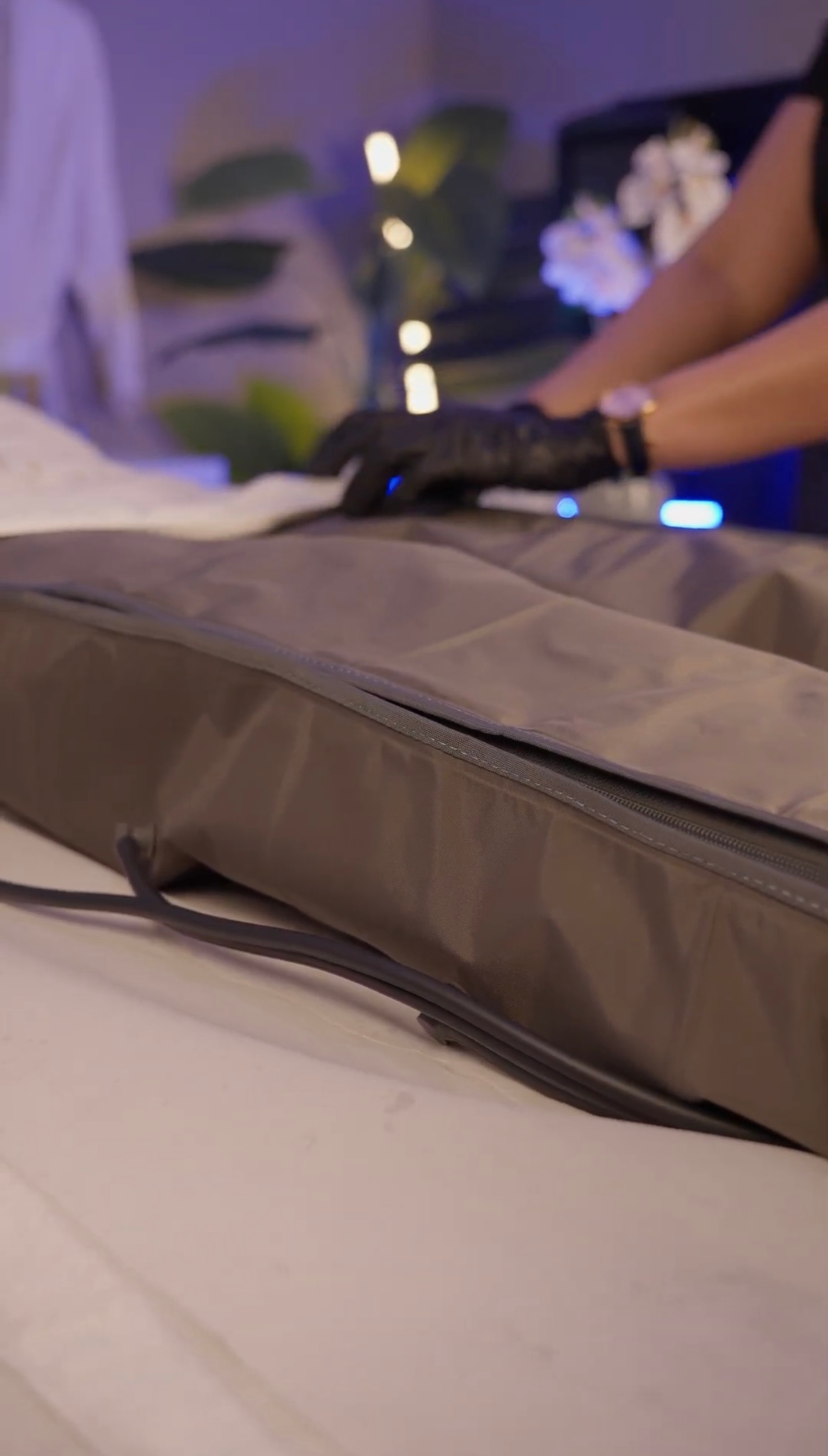 Primer plano de un bolso beige sobre una mesa, con una mano enguantada en una habitación con iluminación tenue.