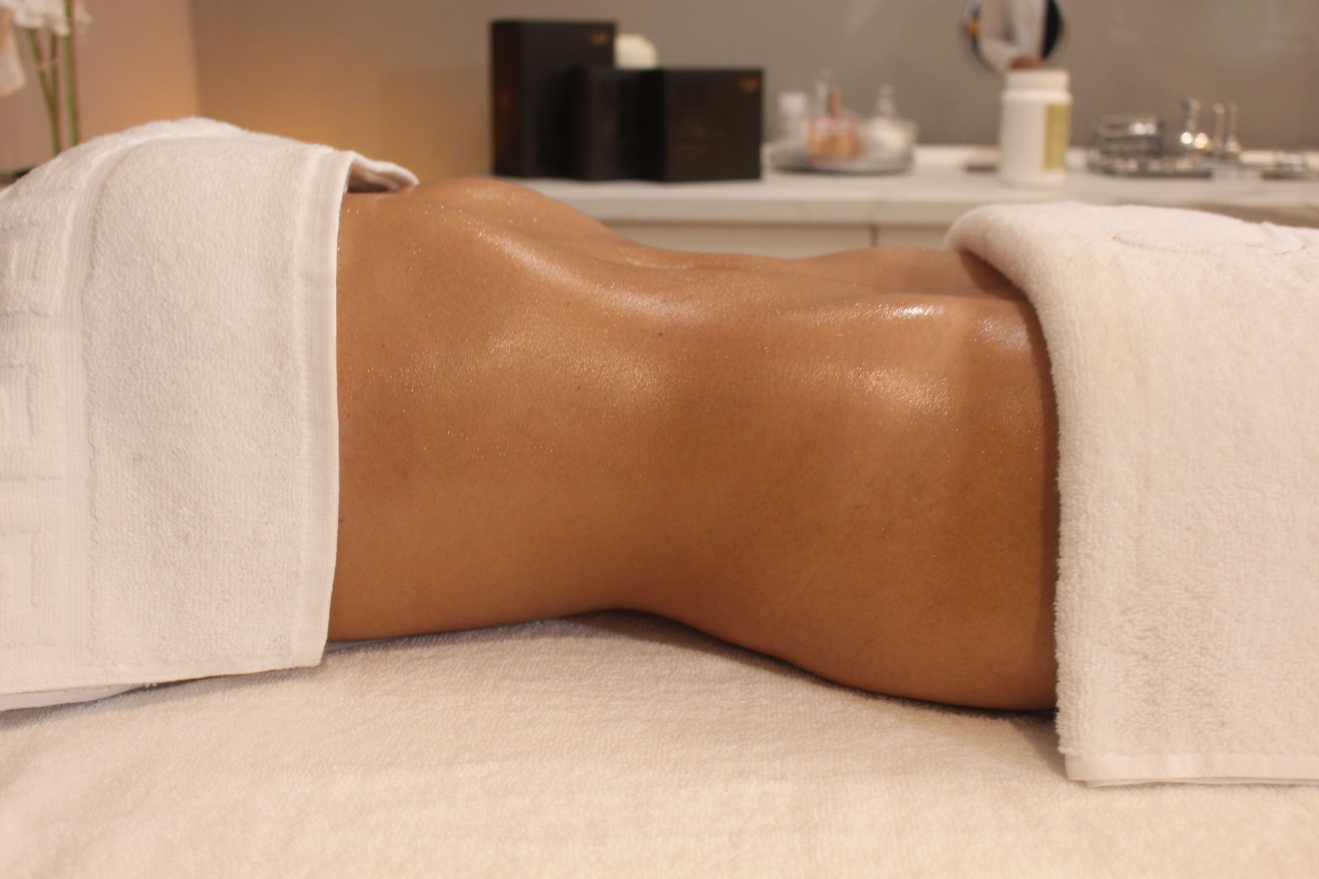 Una mujer está acostada en una mesa de masajes con una toalla blanca en la espalda.