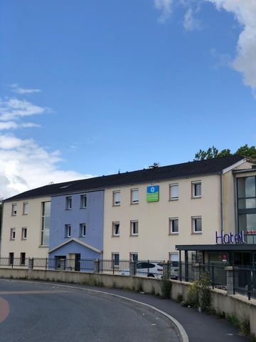 Rue sinueuse avec un hôtel beige et bleu sous un ciel d'un bleu limpide