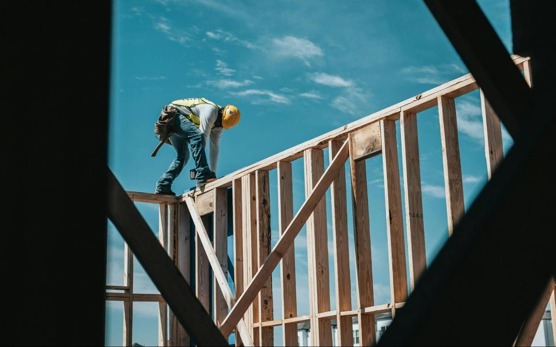 A construction worker is standing on top of a wooden structure.