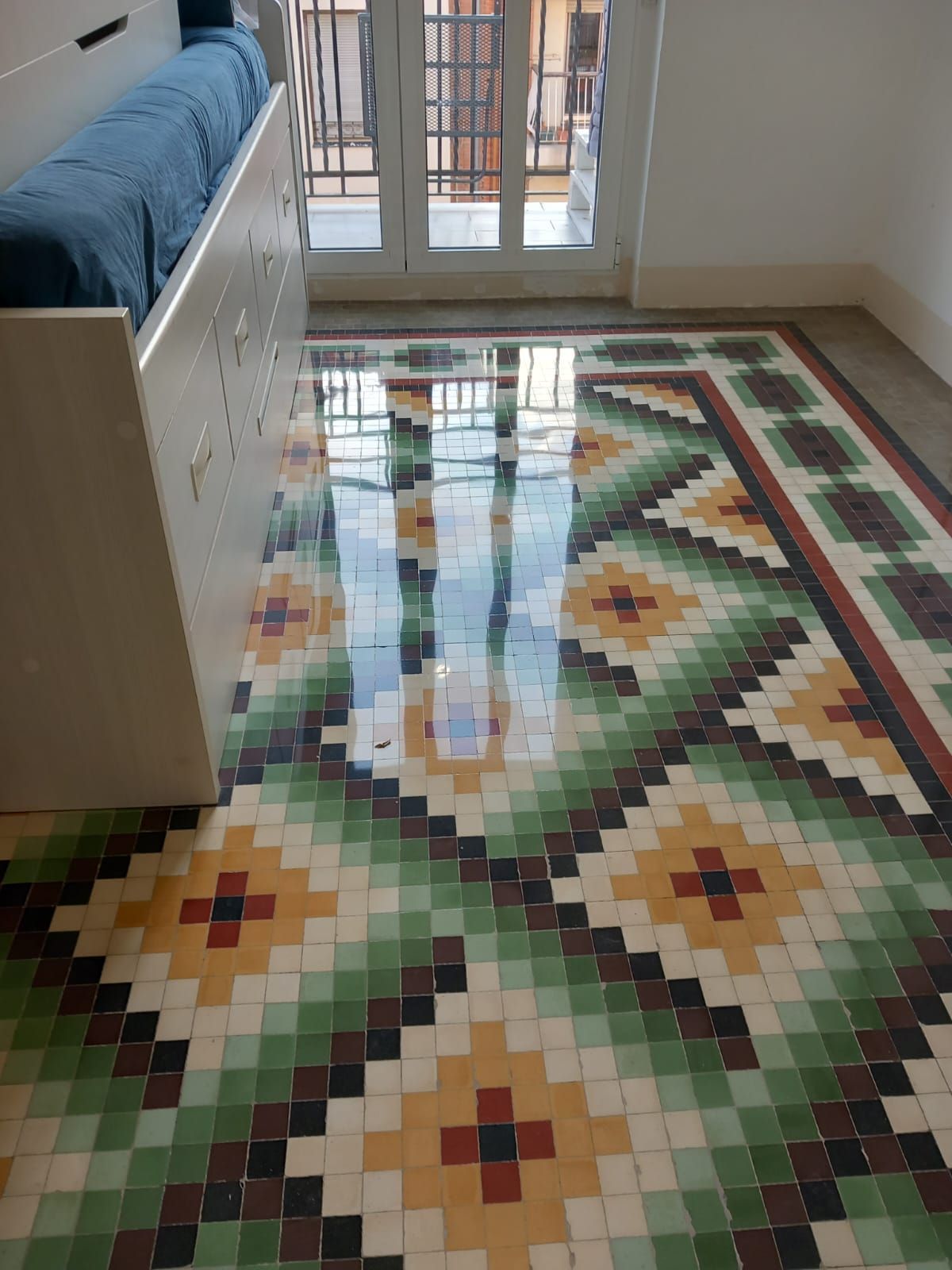 Una habitación con suelo de mosaico y una cama.