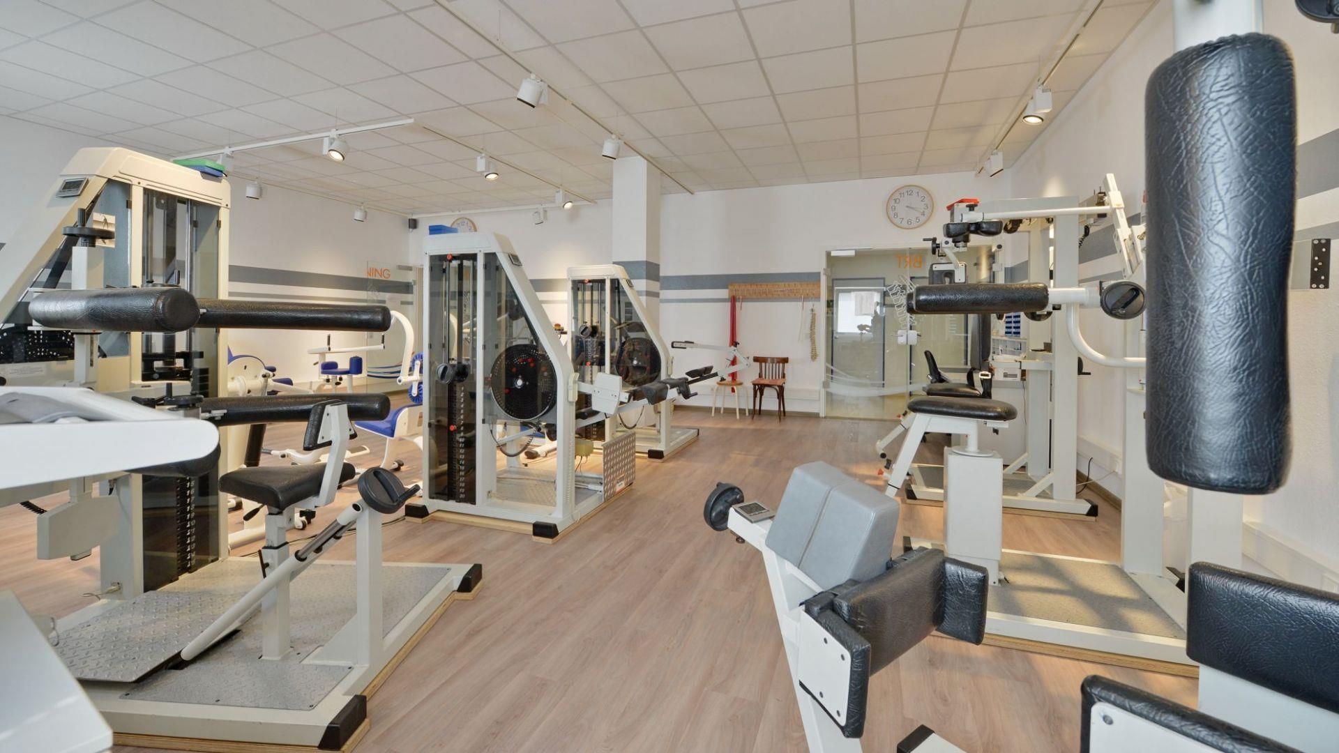Ein Fitnessstudio mit vielen Geräten und einer Uhr an der Wand