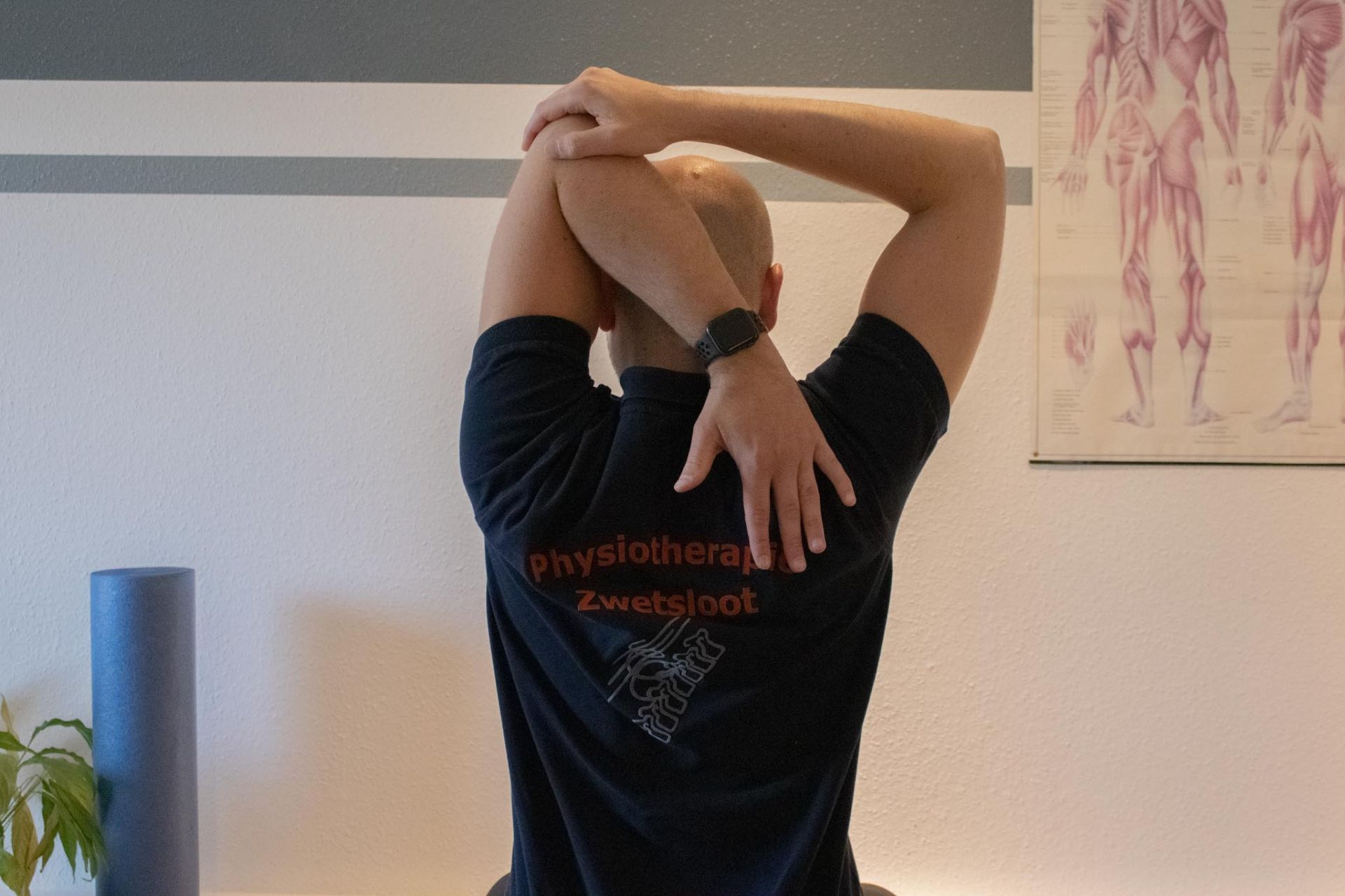Ein Mann trägt ein schwarzes T-Shirt mit der Aufschrift „Physiotherapie“