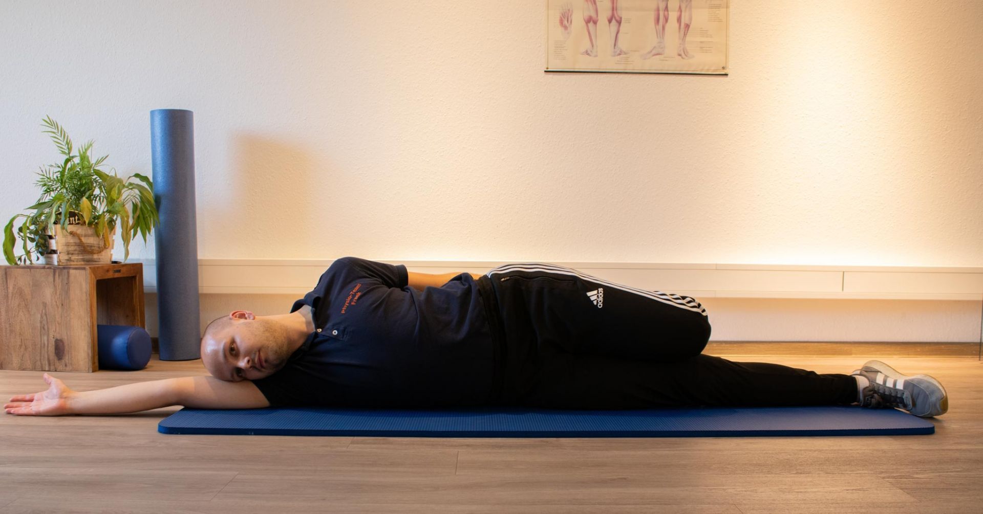 Eine Person liegt mit ausgestreckten Armen auf einer blauen Matte