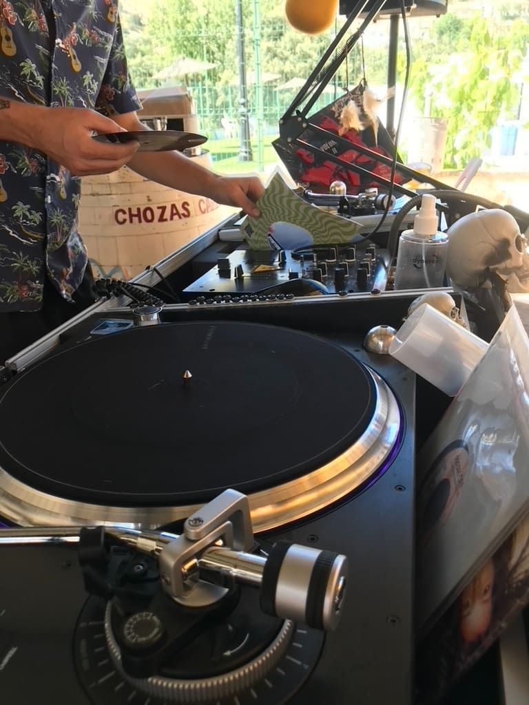 Montaje de tocadiscos para DJ con mezclador y altavoces bajo una carpa al aire libre.