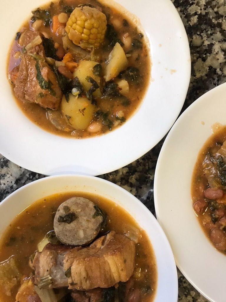 Cuencos de guiso abundante con carne y verduras sobre una encimera moteada.