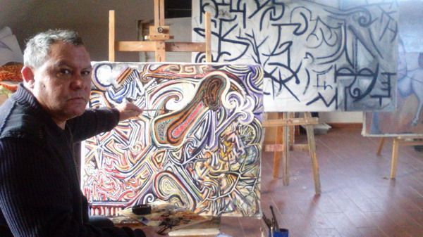 Un hombre señala una pintura abstracta colorida en su estudio.