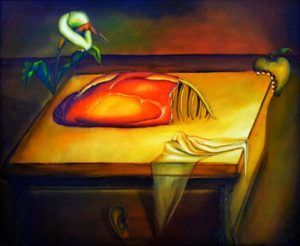 Un objeto en forma de corazón sobre una mesa amarilla con una flor, una manzana y tela; fondo oscuro.