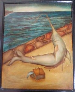 Un pez con un hocico largo se sienta en una playa, al lado de una caja de madera y el océano.