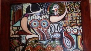 Pintura abstracta de una mujer con un vestido colorido, con un sombrero y un búho en un marco de madera.