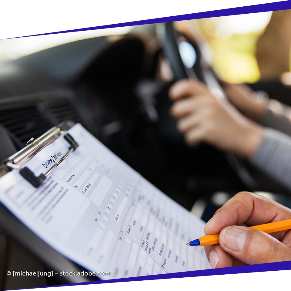 Fahrlehrer von [company_name]  füllt das Formular aus, während der Fahrschüler am Steuer sitzt