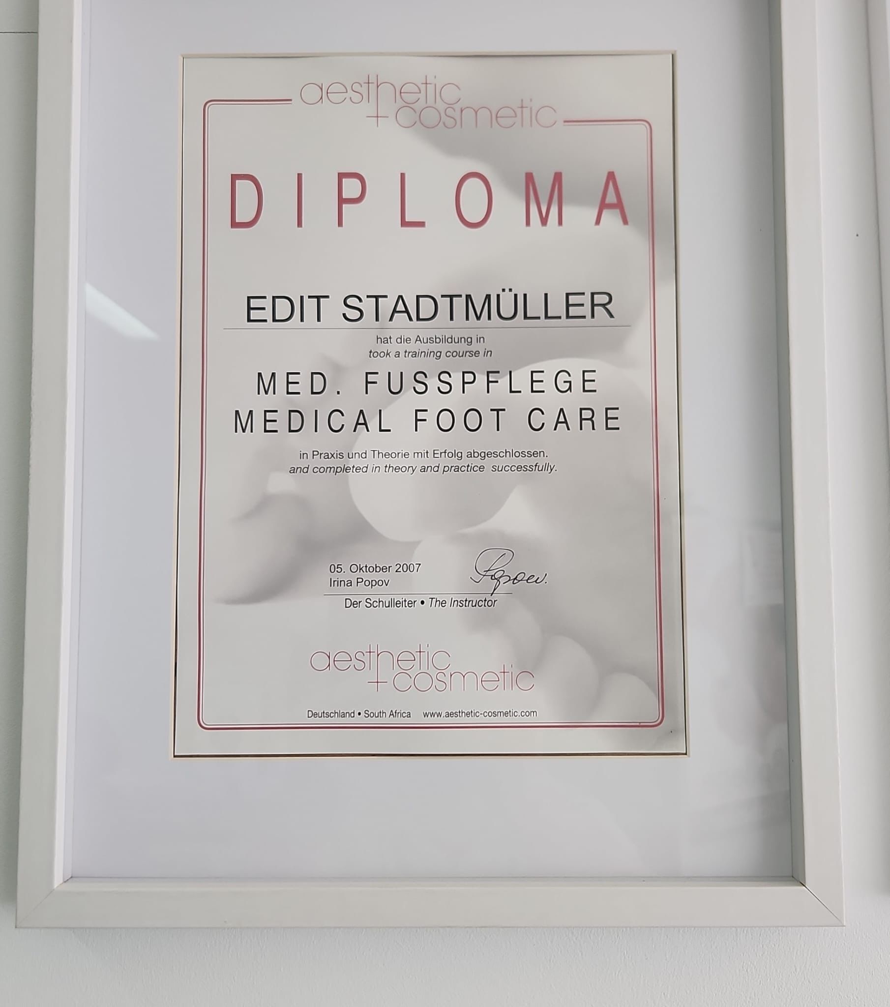 Ein Diplom hängt gerahmt an einer weißen Wand