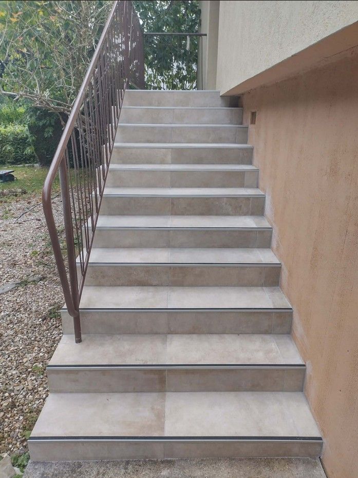 Escalier extérieur en béton avec murs beiges et rampe métallique à gauche