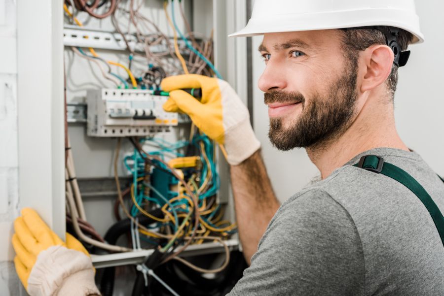 Freundlicher Elektriker an Stromkasten