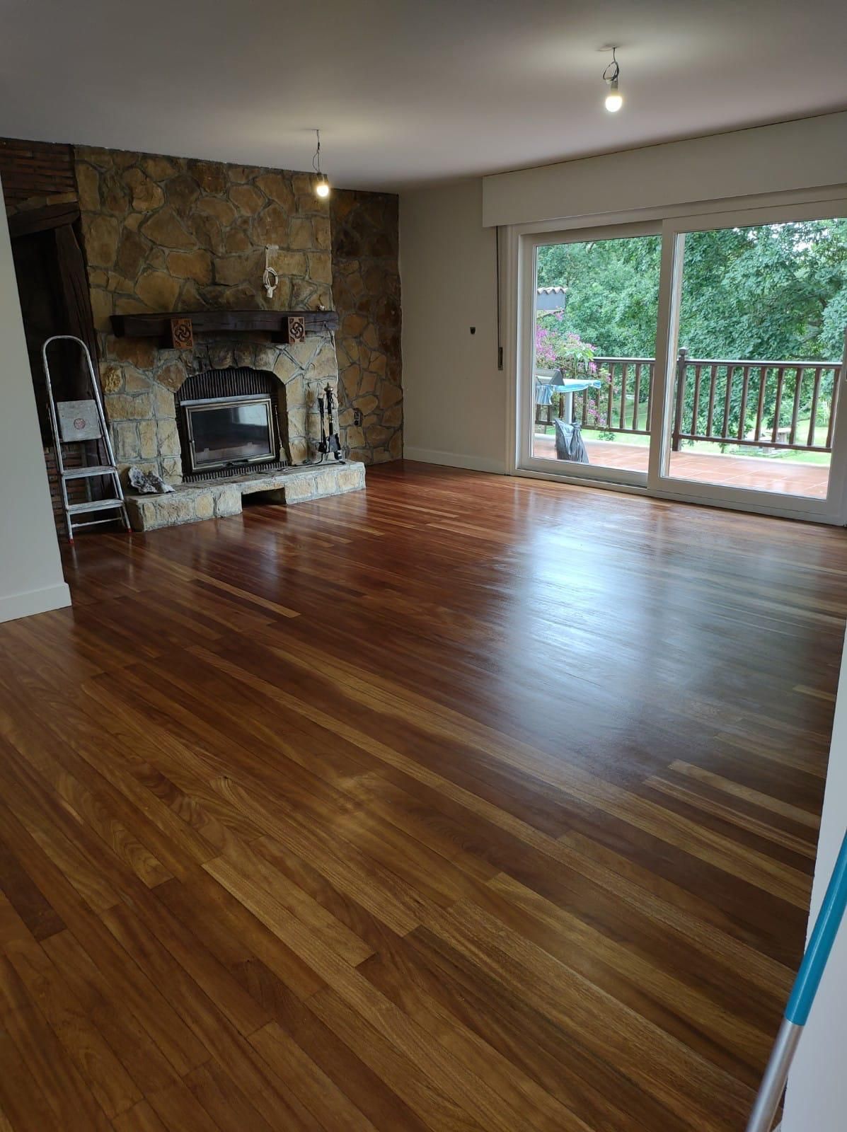 Sala de estar con pisos de madera, chimenea de piedra y puerta corrediza de vidrio a una terraza.