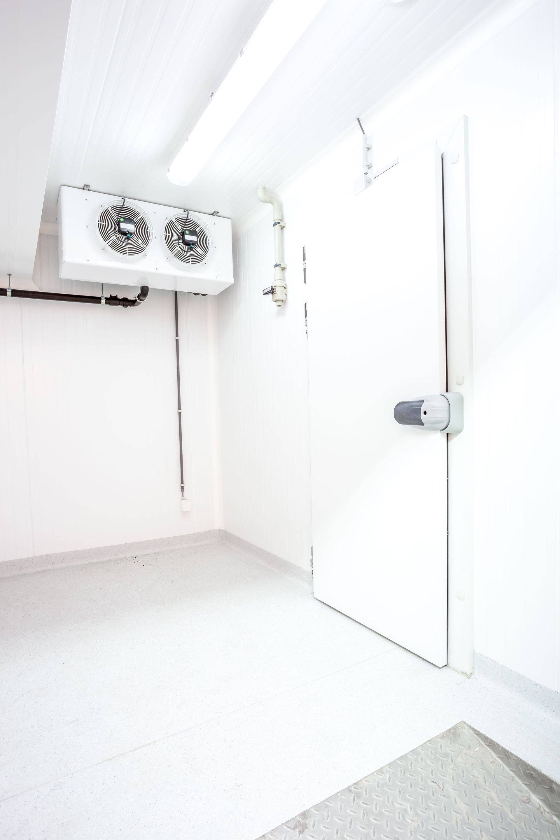 Una habitación vacía con una puerta y dos ventiladores colgando del techo.