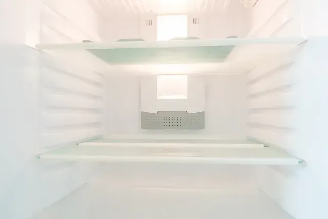 El interior de un refrigerador vacío con una luz encendida.