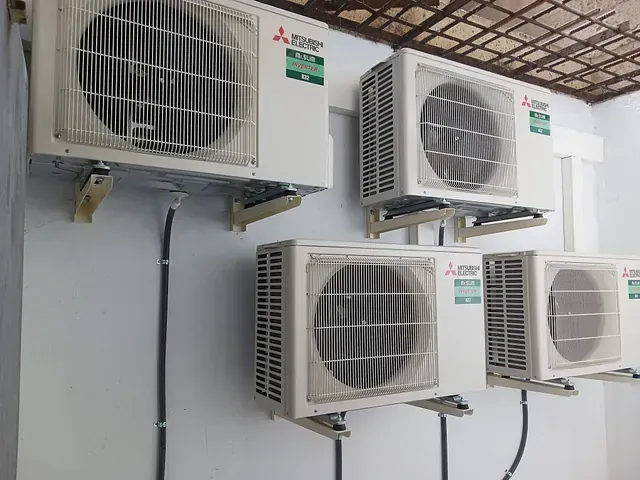 Una fila de acondicionadores de aire montados en una pared.