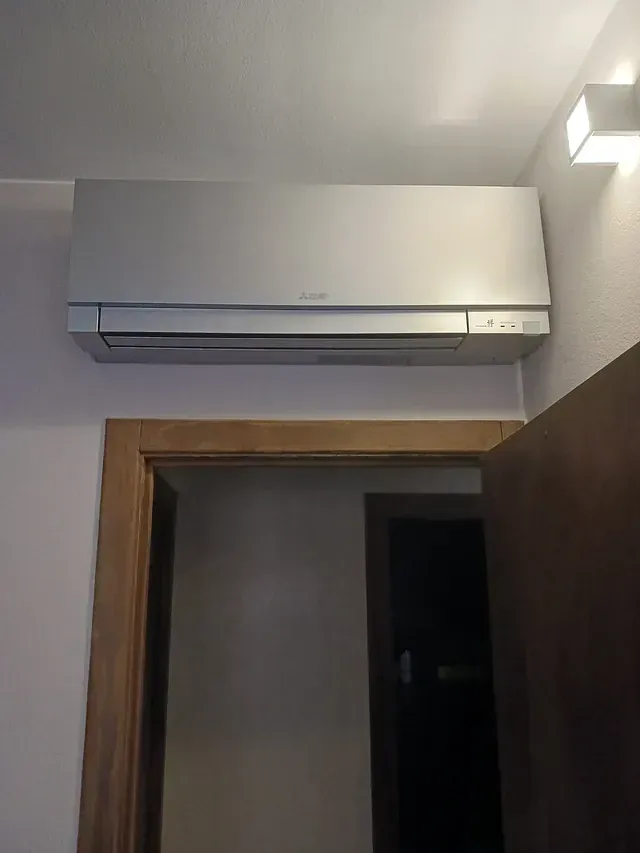 Un aire acondicionado montado en la pared en una habitación al lado de una puerta.