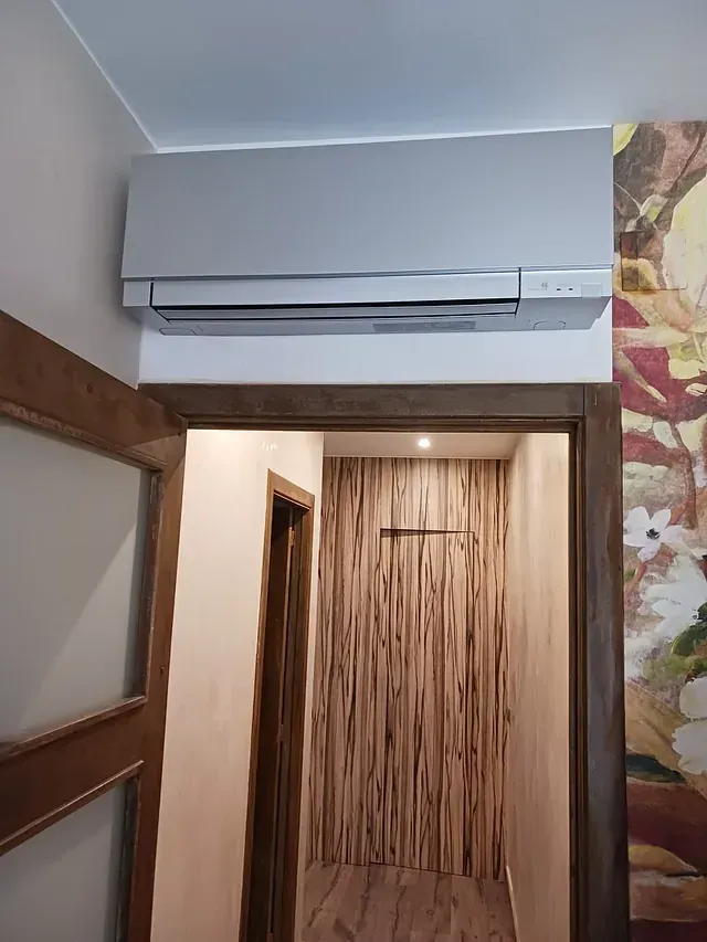 Un pasillo con un cuadro en la pared y un aire acondicionado montado en la pared.