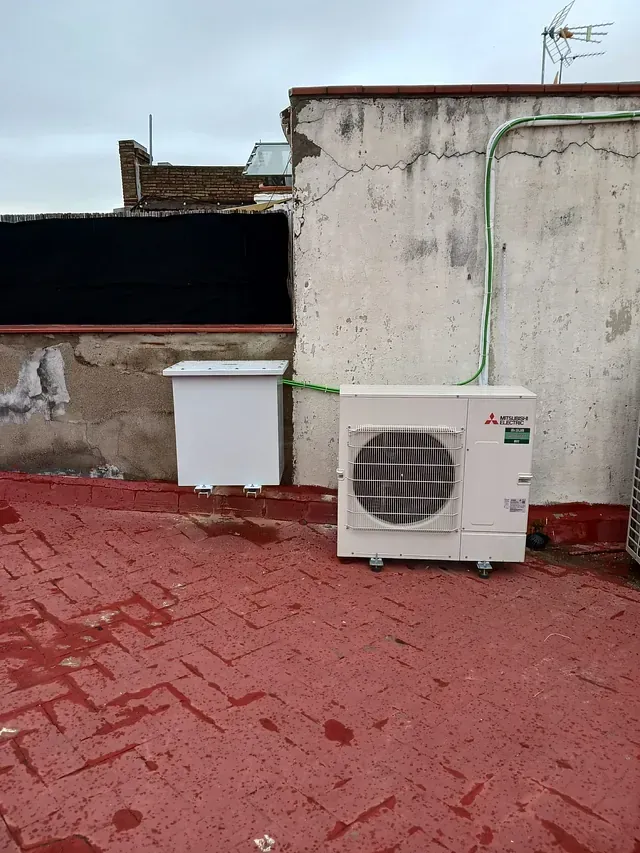 Un acondicionador de aire blanco está situado en el techo de un edificio.