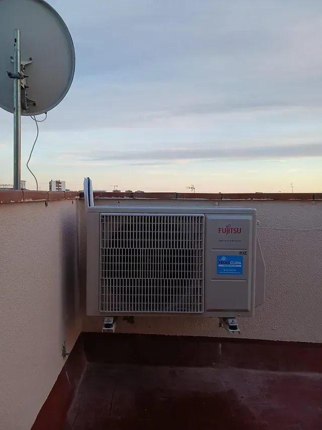 Un aparato de aire acondicionado en un tejado con una antena parabólica al fondo