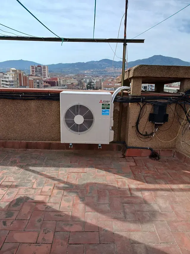 Un acondicionador de aire blanco está situado encima de un patio de ladrillo.