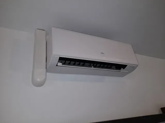 Un acondicionador de aire blanco está colgado en una pared blanca.