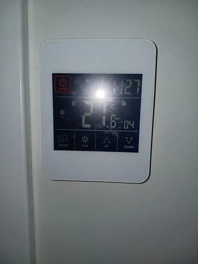 Un termostato blanco está colgado en una pared blanca.