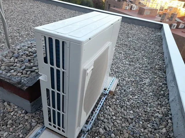 Un acondicionador de aire blanco está situado encima de un techo rocoso.