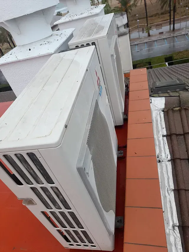 Una fila de aparatos de aire acondicionado están colocados encima de un tejado.