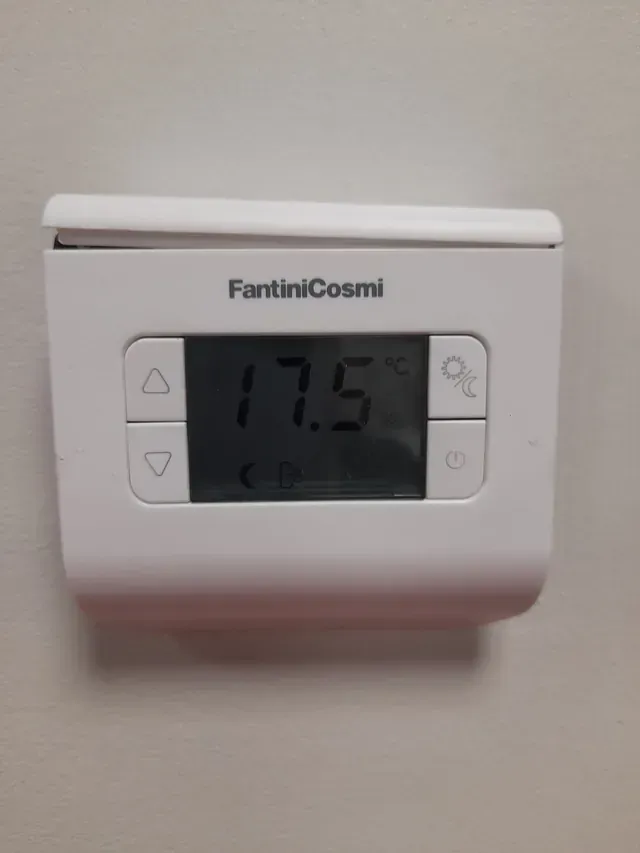 Un termostato Fantini Cosmi blanco está colgado en una pared blanca.