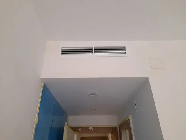 Un pasillo con un techo blanco y una pared azul.