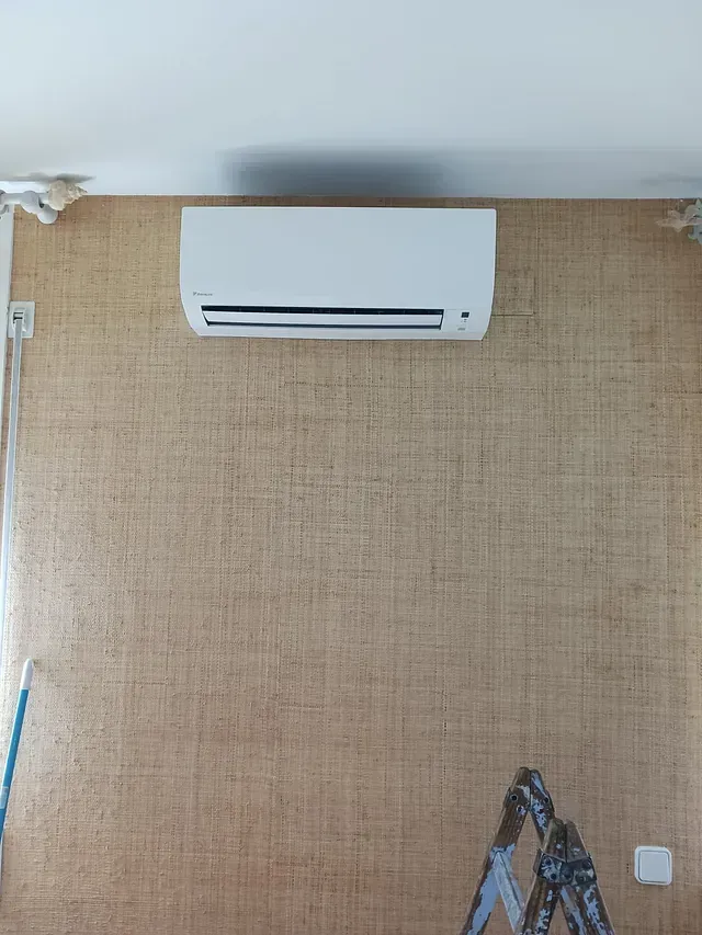 Un acondicionador de aire blanco está colgado en una pared al lado de una escalera.