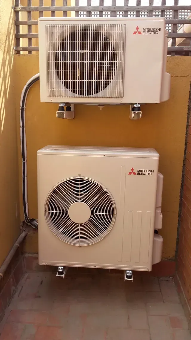 Dos aparatos de aire acondicionado están montados en una pared en un balcón.