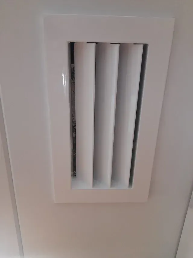 Un respiradero blanco cuelga del techo de una habitación.