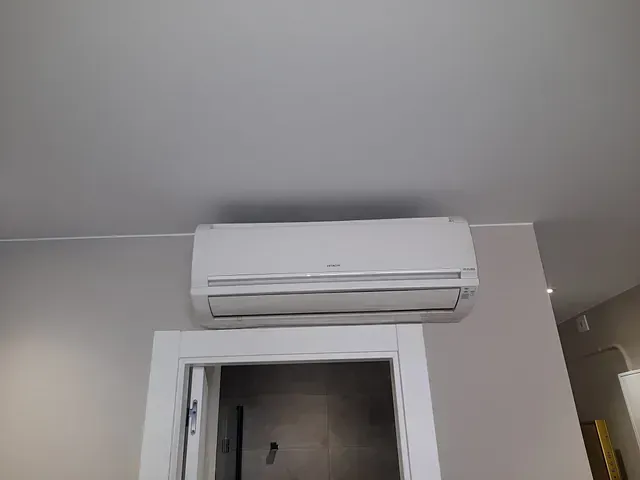 Un acondicionador de aire blanco cuelga del techo encima de una puerta.