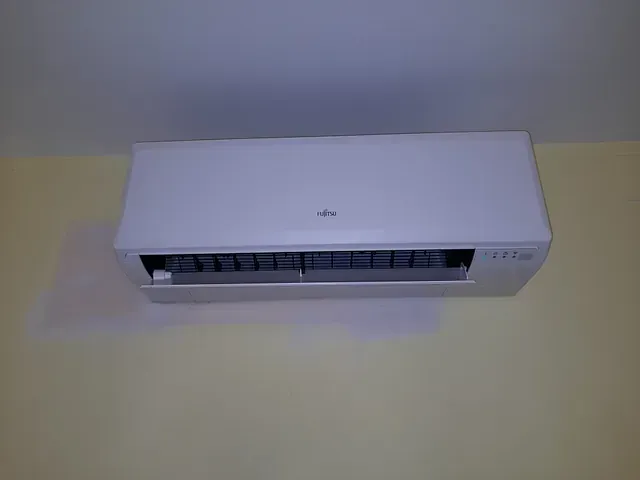 Un acondicionador de aire blanco está colgado en una pared amarilla.