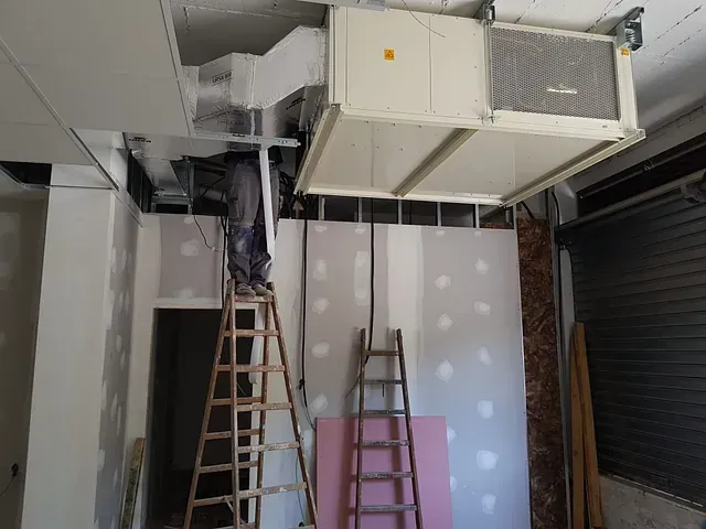 Un hombre está de pie en una escalera en una habitación en construcción.