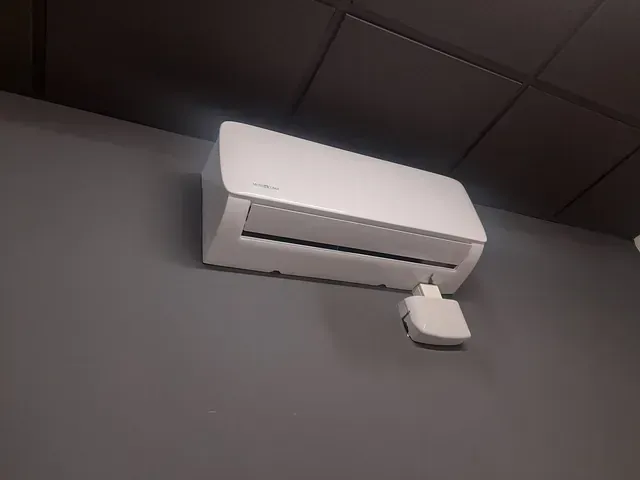 Un acondicionador de aire blanco está montado en una pared gris.