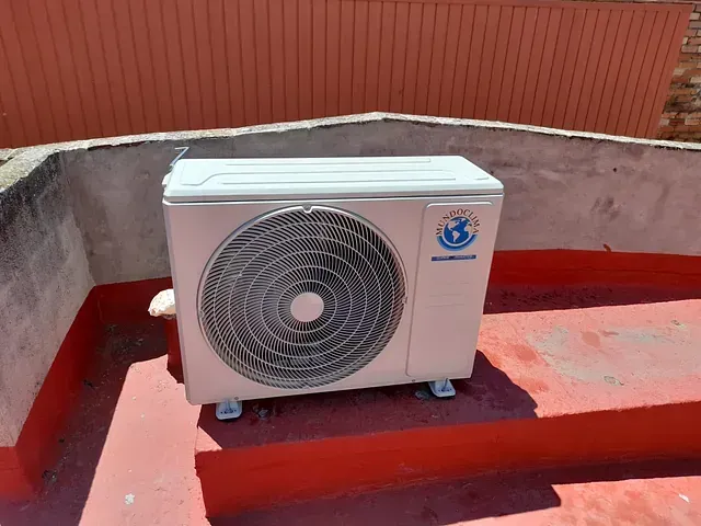 Un acondicionador de aire blanco está situado encima de un techo rojo.