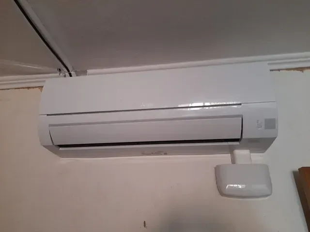 Un acondicionador de aire blanco está colgado en la pared de una habitación.