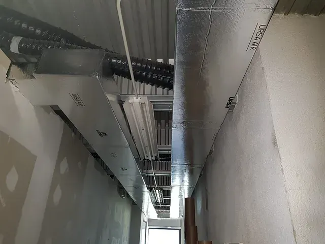 Un largo pasillo con muchas tuberías colgando del techo.